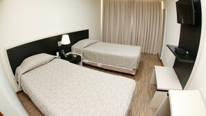 A hotel room with two beds, a desk, a TV, and a window with curtains. - Hotel Financial Ltda (Belo Horizonte)