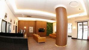 A modern lobby with a reception desk, sofas, a large wooden pillar, and a green wall. - Hotel Financial Ltda (Belo Horizonte)