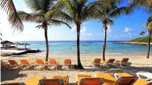 A beach with rows of sun loungers and palm trees. - O' calme studio accommodation paradise sea view (Saint François)