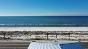 A beach view with a road in the foreground and a clear blue sky.