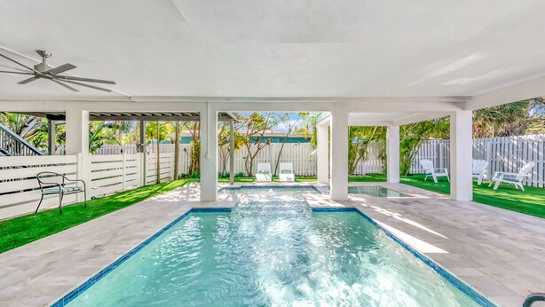 A swimming pool with a ceiling fan, surrounded by a white fence and a white picket fence. - You, Me, and the Sea AMI - Elevated Beach Home with Pool and Spa Steps from Beac (Holmes Beach)