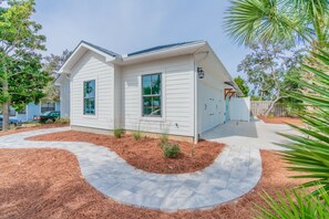 Ein zweistöckiges Haus mit Veranda, Garage und einem angelegten Garten mit Mulch und kleinen Pflanzen.