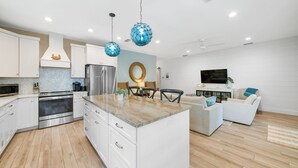 Una cocina moderna con armarios blancos, electrodomésticos de acero inoxidable y una encimera de mármol.
