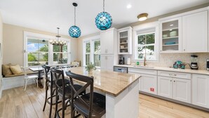 Una cocina moderna con armarios blancos, encimera de granito y un comedor con banco y sillas.