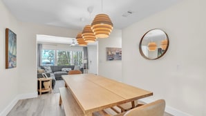 A modern dining area with a wooden table and benches, pendant lights, and a round mirror on the wall.