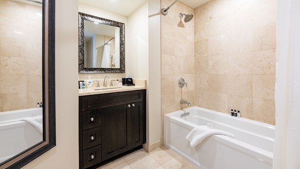 Een moderne badkamer met een bad, een douche en een wastafel met spiegel.