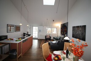 A modern kitchen with a dining area, featuring a central island, a sofa, and a table set for dining.