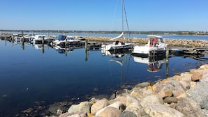 Un port de plaisance avec des bateaux amarrés, une eau calme et une côte rocheuse.
