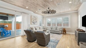 A spacious living room with a large window, a ceiling fan, and a sliding glass door leading to an outdoor area.