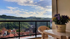 Un balcón con vista a un pueblo, una mesa con una planta en maceta y una silla.