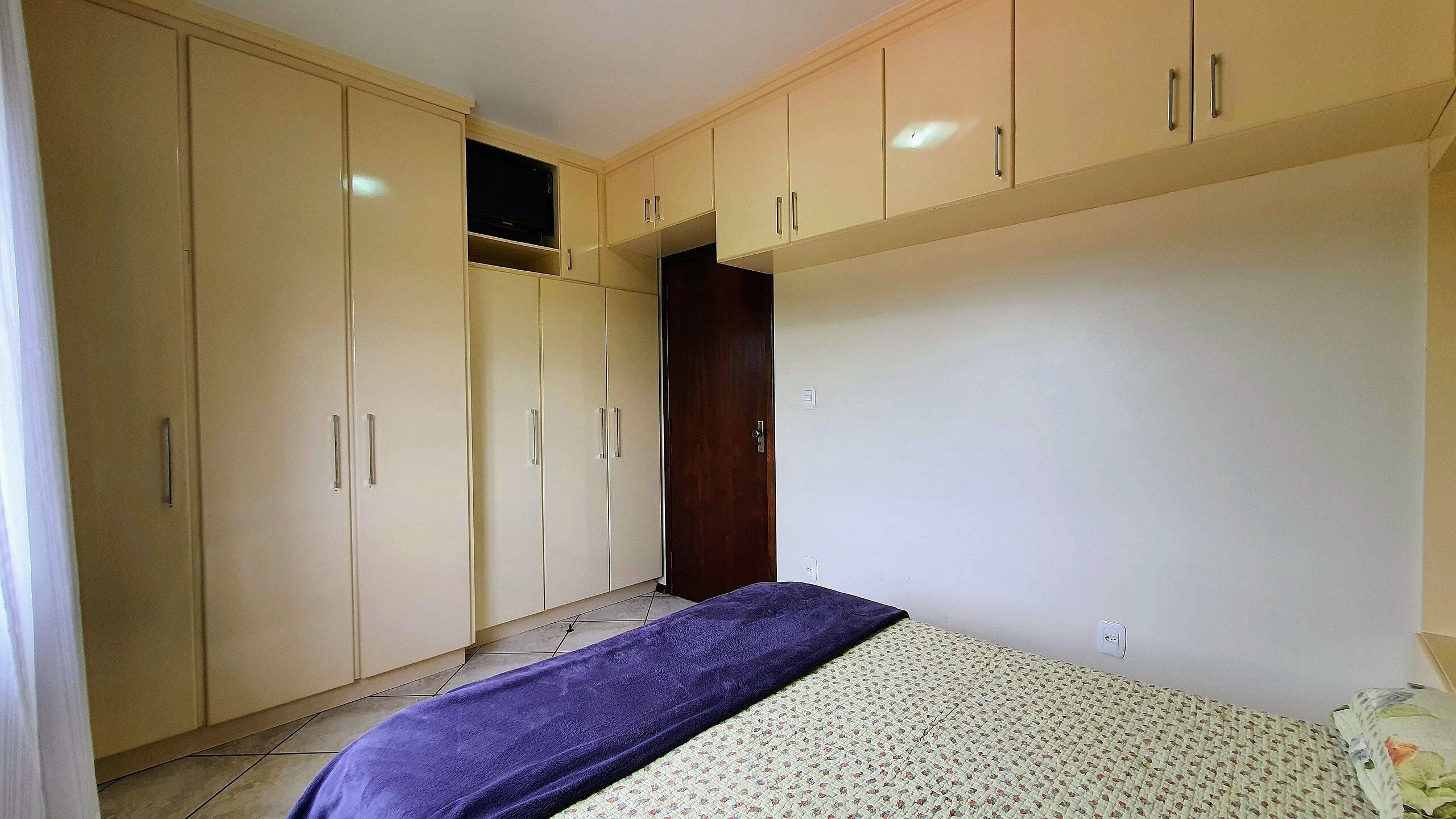 A bedroom with a bed, a wardrobe, and a door.