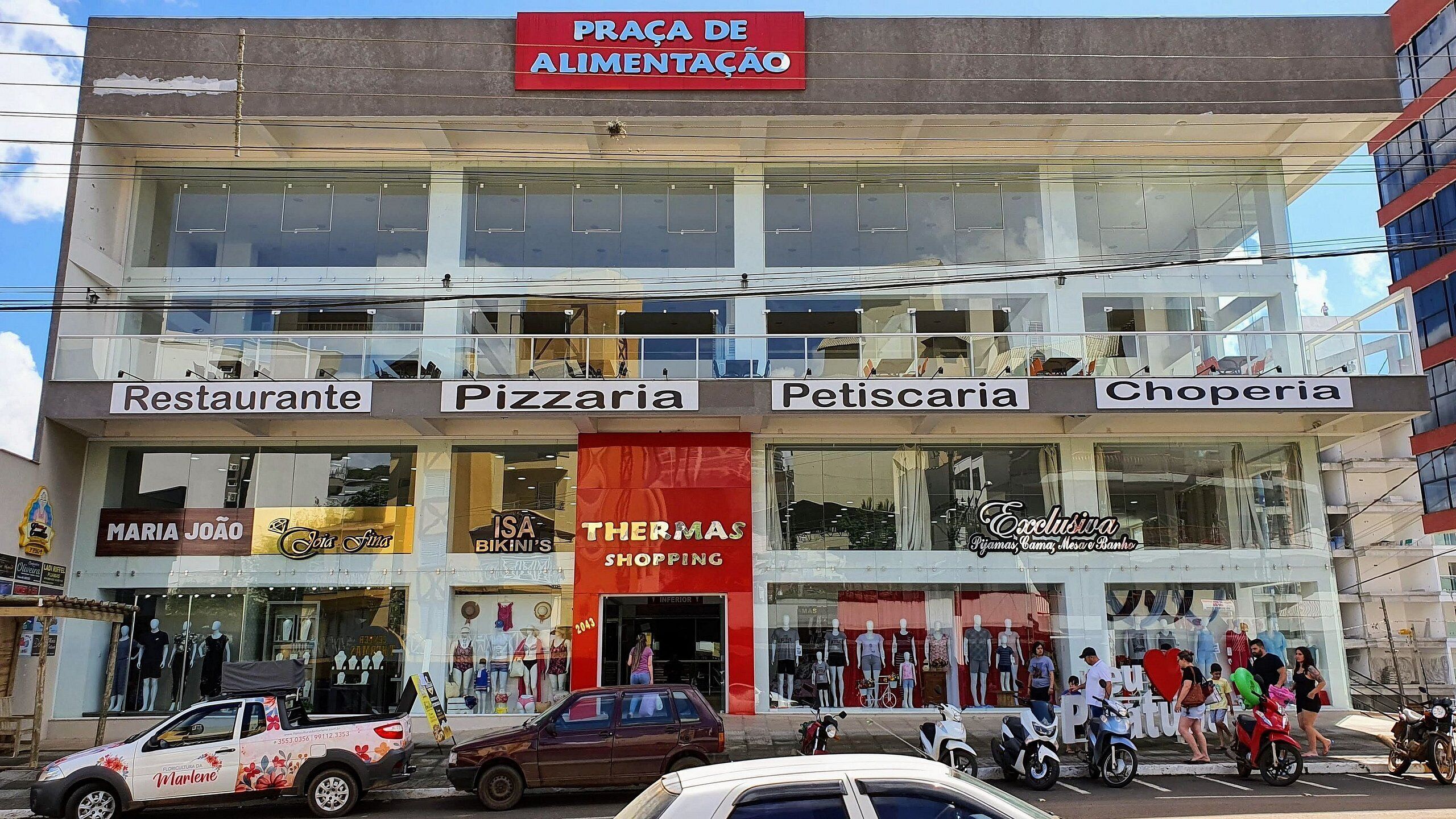 A multi-story building with various shops on the ground floor, including a restaurant, pizzeria, pet store, and clothing store.