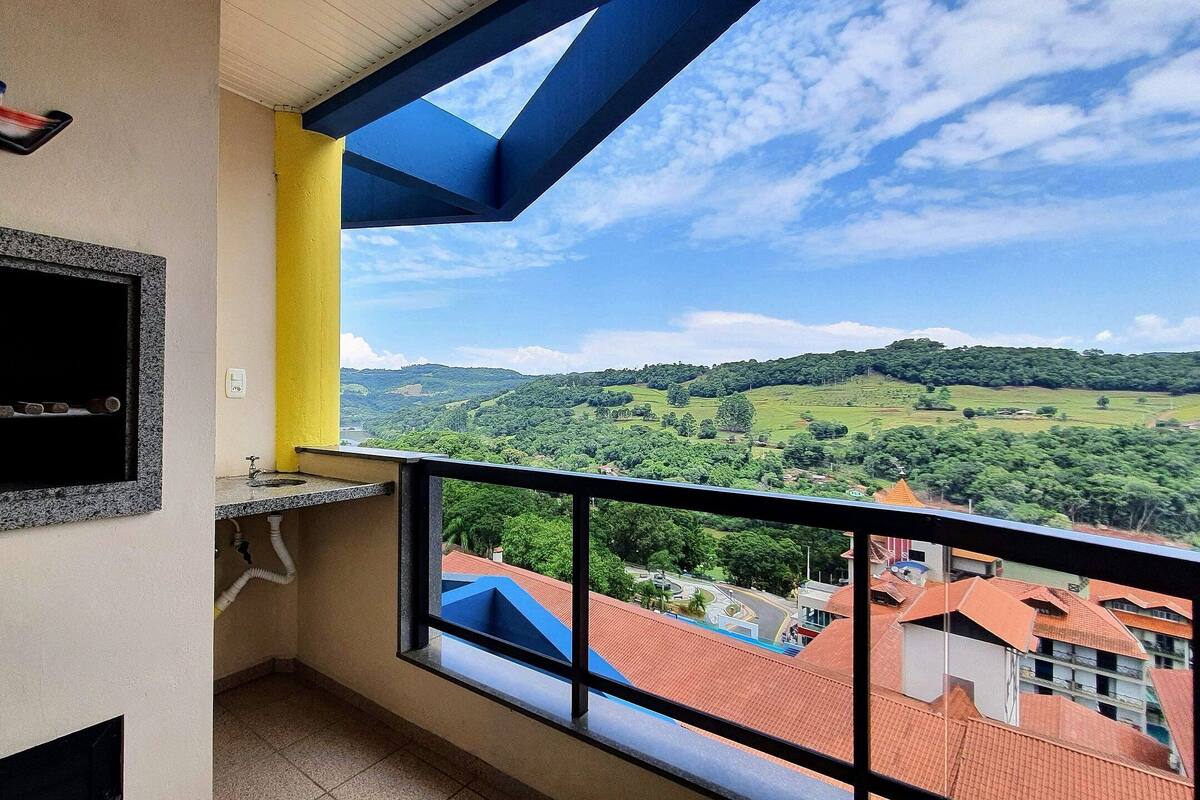 A balcony with a view of green hills and a distant town.