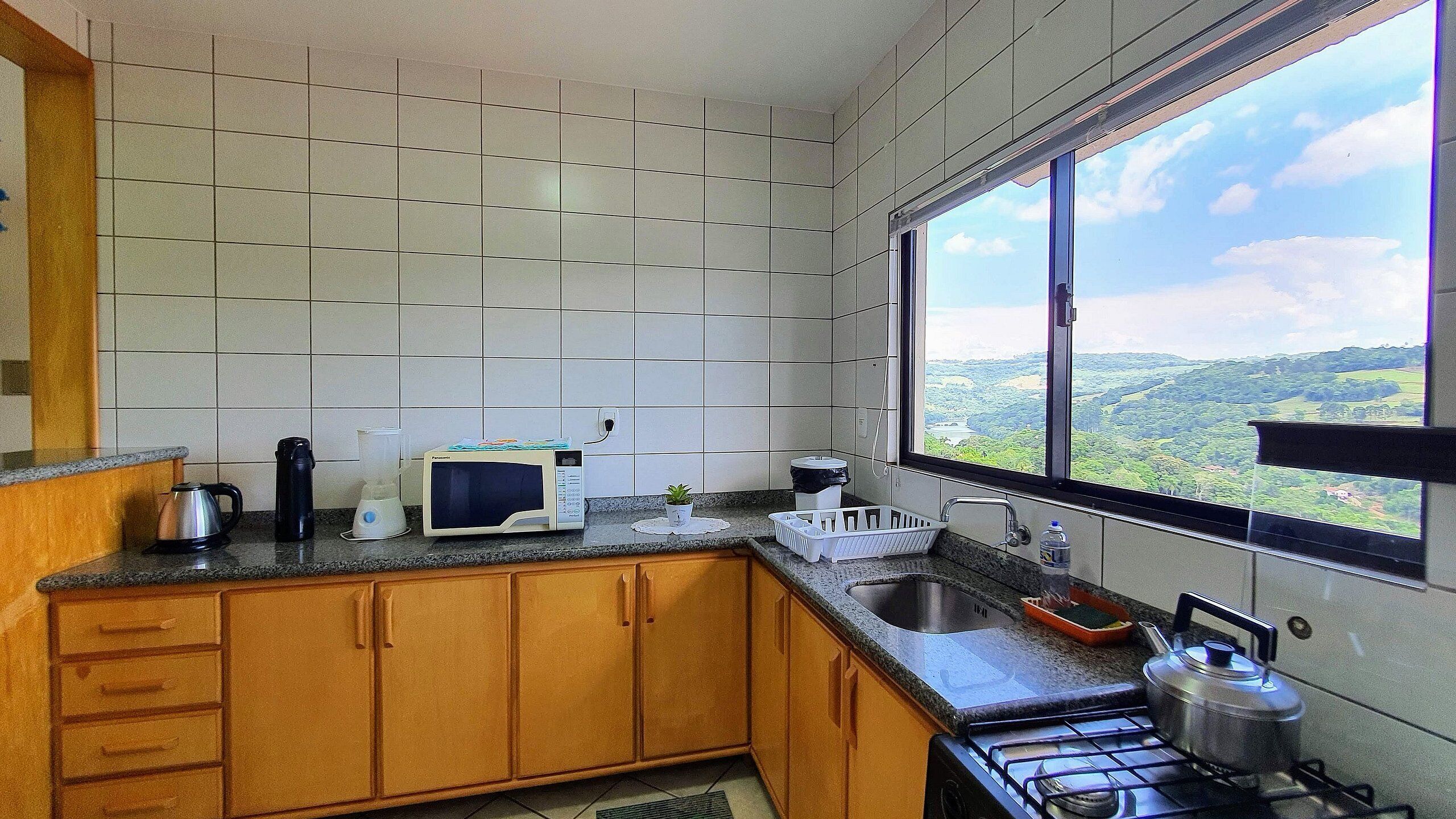 Une cuisine donnant sur un paysage verdoyant, visible à travers une fenêtre.