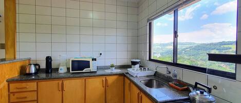 Une cuisine donnant sur un paysage verdoyant, visible à travers une fenêtre.