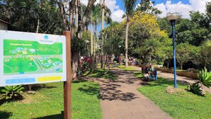 Un parque con un cartel de mapa, senderos, bancos y abundante vegetación.
