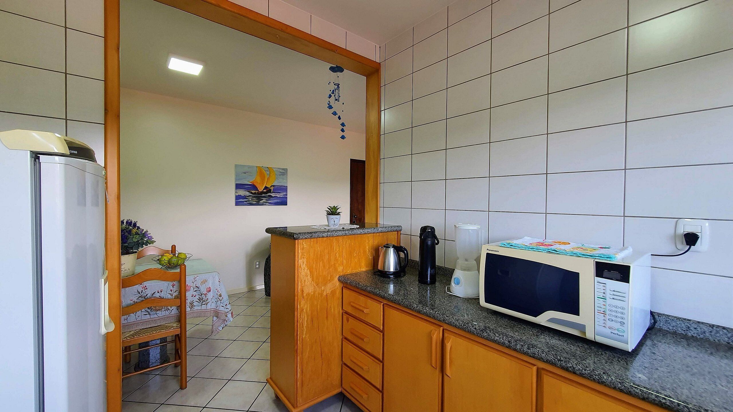 Una cocina equipada con refrigerador, microondas, hervidor y un armario de madera.