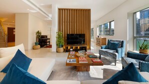 Ein modernes Wohnzimmer mit Fernseher, einem Klavier und einem Couchtisch mit Büchern.