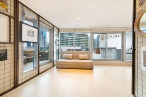 Un amplio salón con un sofá, una mesa de comedor y vistas a rascacielos.