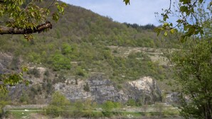 Zona junto a la piscina con dos sillones de descanso, una mesita con bebidas y vistas a un río y colinas.