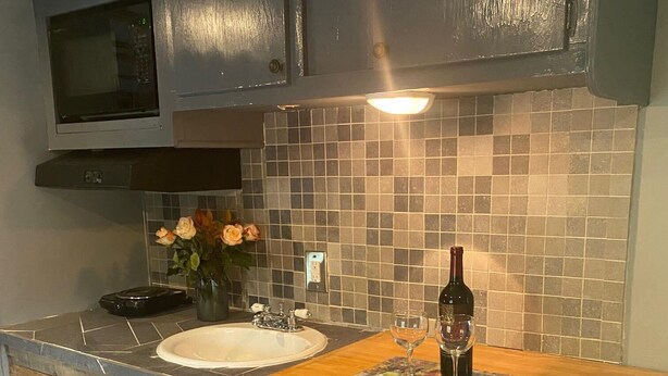 Eine Küche mit Holzausziehtisch, Spüle und einer Weinflasche.