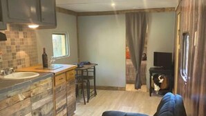 Ein kompaktes Wohnmobil-Interieur mit einer Küchenzeile, einer Sitzecke und einer kleinen Entertainment-Einheit.