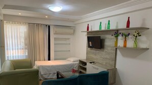 Una habitación de hotel moderna con cama, escritorio, televisión y un área de descanso con dos sillones.