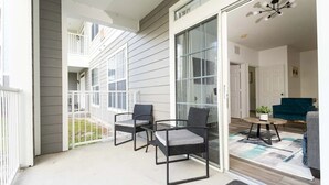 Un balcon avec des fauteuils en osier, une petite table et un pot de fleurs.
