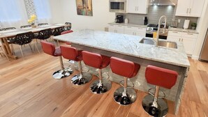 Una cocina moderna con encimera de mármol, electrodomésticos de acero inoxidable y taburetes de bar rojos.