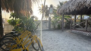 A bicycle parked near a gate with a thatched roof structure and a fence in the background.