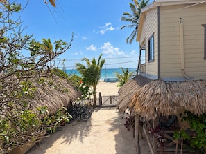 A beachside property with a thatched-roof structure, bicycles, and a view of the ocean. - CAYLO Hotel (Caye Caulker)