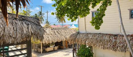 A beachside area with thatched-roof structures, outdoor seating, and a white building.