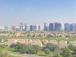 A residential area with modern and traditional buildings, a clear sky, and a well-maintained green space.