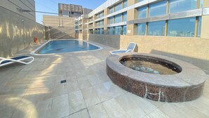 A rooftop pool area with a hot tub, lounge chairs, and a view of the city skyline. - Lux BnB Elite Residences I Golf Course Views (Dubai)