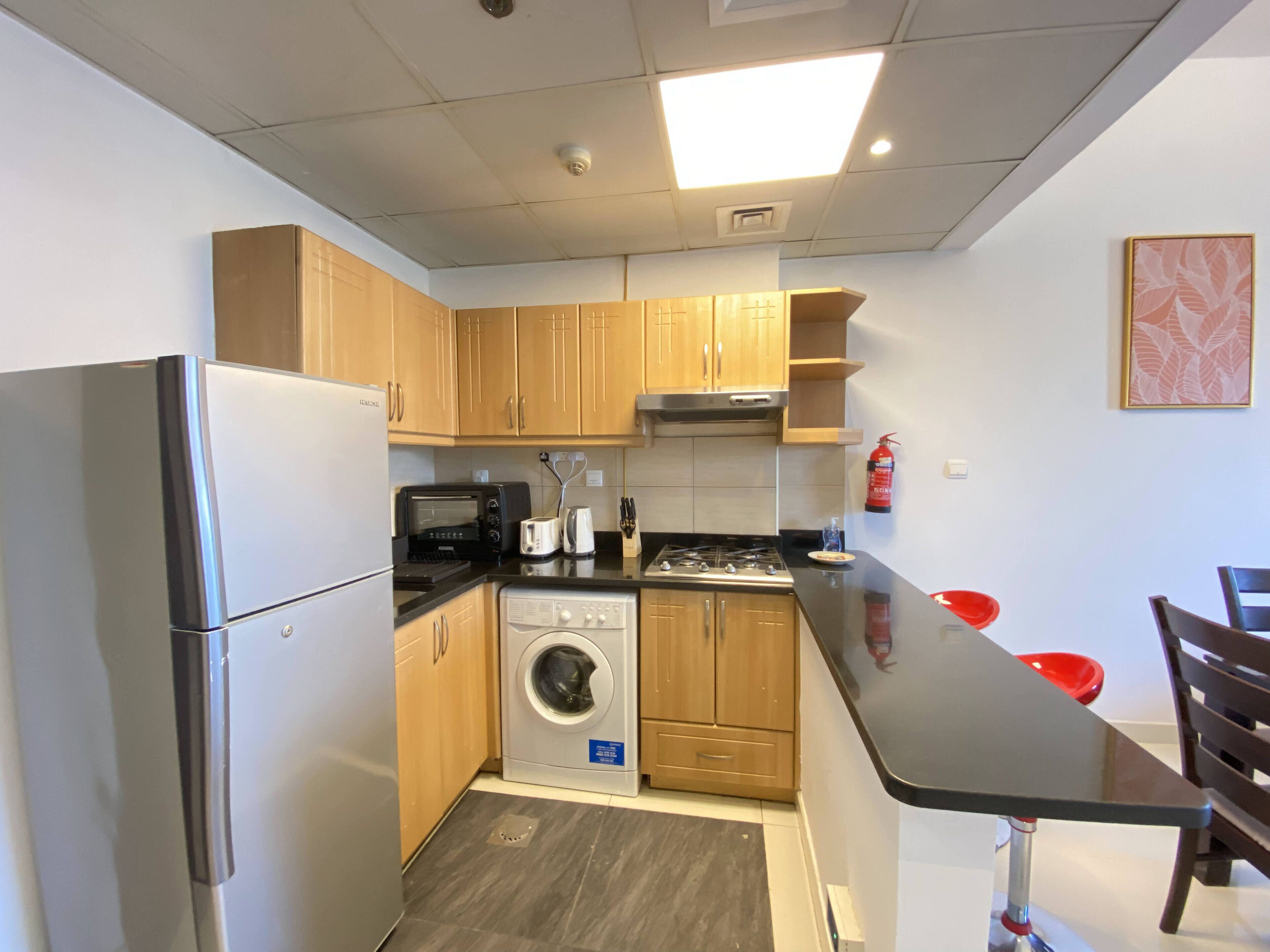 Eine kompakte Küche mit Kühlschrank, Mikrowelle, Toaster, Spüle und Waschmaschine.