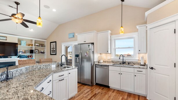 A modern kitchen with white cabinets, granite countertops, a stainless steel refrigerator, and a ceiling fan. - Another Day In Paradise: 4-Min Walk to the Beach! (Kill Devil Hills)