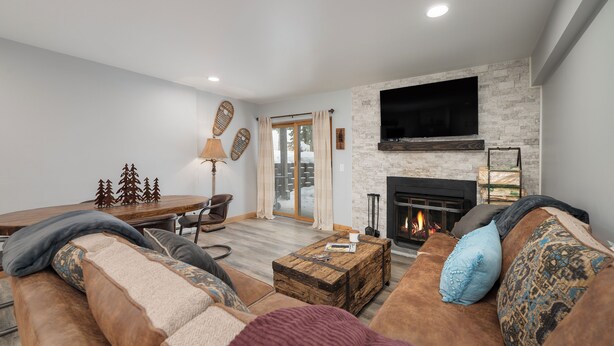 Una sala moderna con chimenea, un televisor grande y una zona de estar acogedora.