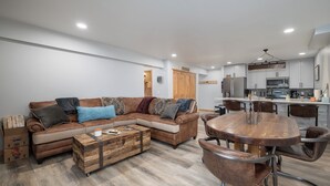 Una sala de estar moderna con un sofá seccional, una mesa de centro de madera y una mesa de comedor redonda con sillas.