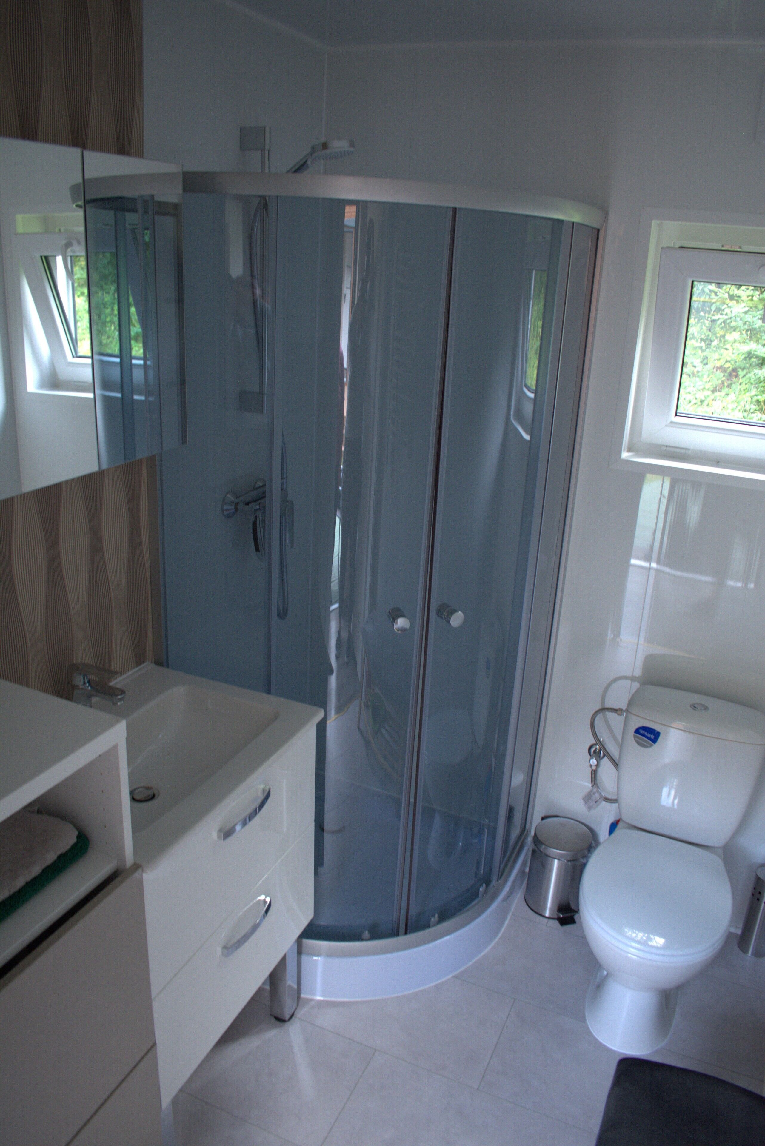 A modern bathroom with a glass-enclosed shower, a white sink, and a toilet.