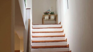 A staircase with wooden steps leading to a landing area with a small table and decorative items. - Villa Ocenano  - Stunning Ocean Views (Albufeira)