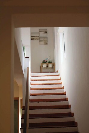 Un escalier avec des marches en bois menant à un palier où se trouvent une petite table et des objets décoratifs.