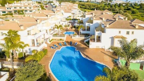 Ein Resort mit Swimmingpool, umgeben von Palmen und Liegestühlen.