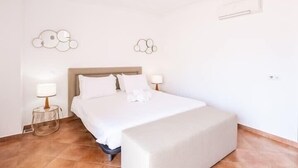 Ein ordentlich eingerichtetes Schlafzimmer mit einem Bett, Nachttischlampen und dekorativer Wandkunst.