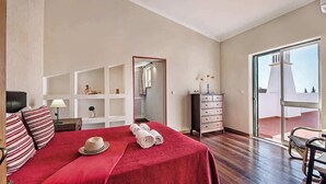 Un dormitorio amplio con una cama grande, un aparador y vistas al exterior a través de una puerta corredera de vidrio.