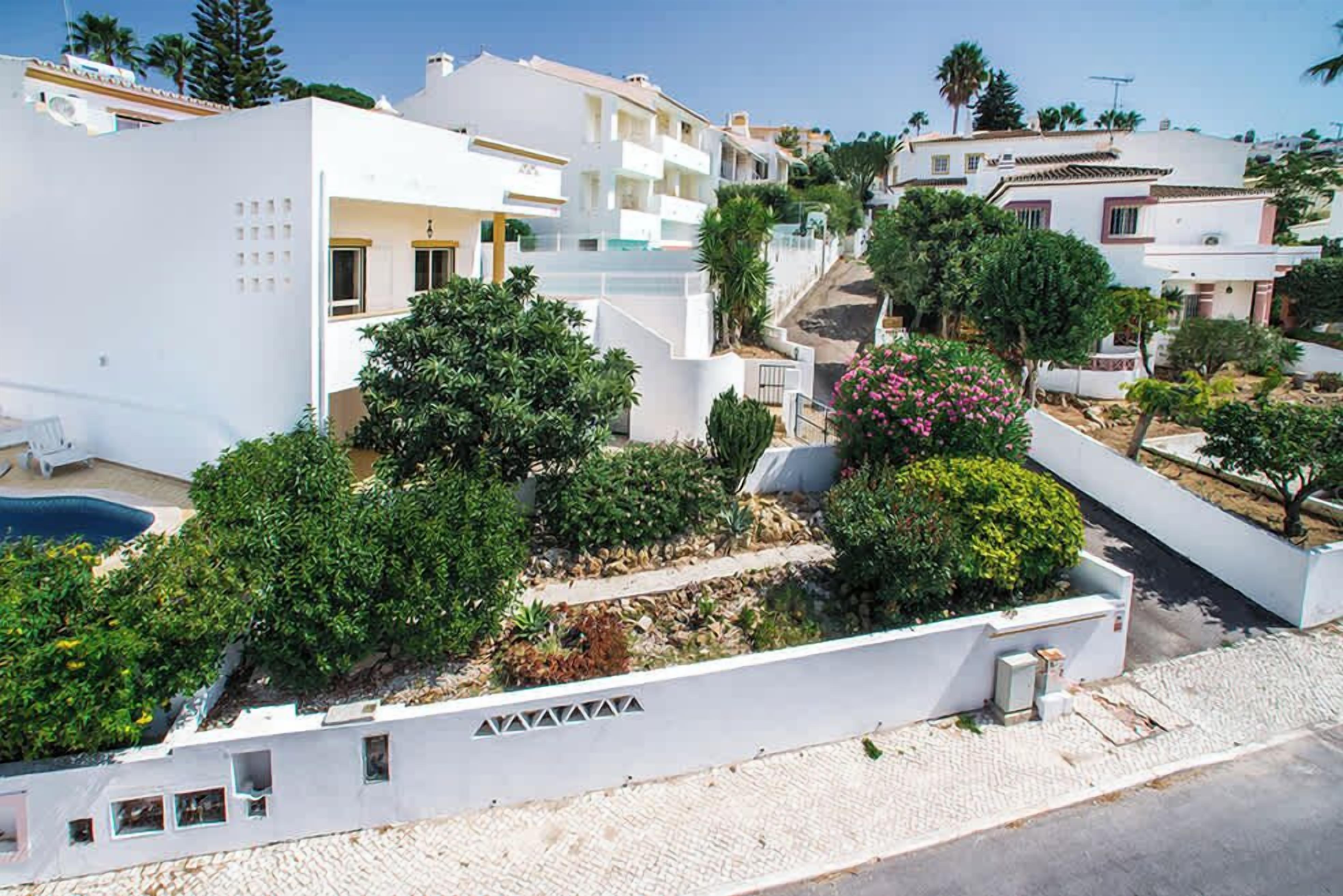Zona residencial con edificios blancos, piscina y jardines cuidados.