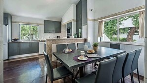 Una cocina moderna con armarios oscuros, una isla central y una zona de comedor con mesa y sillas.