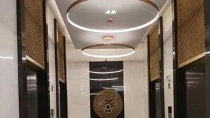A modern hallway with a central art piece, recessed lighting, and a patterned floor.