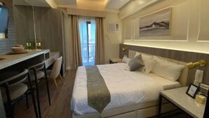A modern hotel room with a bed, desk, and chairs.