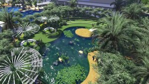 A landscaped area with a central pond, surrounded by palm trees and a circular walkway.