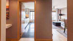 Une chambre d’hôtel moderne avec un plancher en bois, un canapé, une petite table et un téléviseur.
